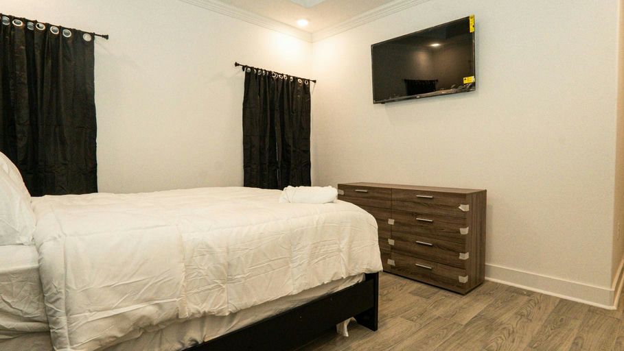 A tidy bedroom with a made bed, dresser and wall-mounted TV